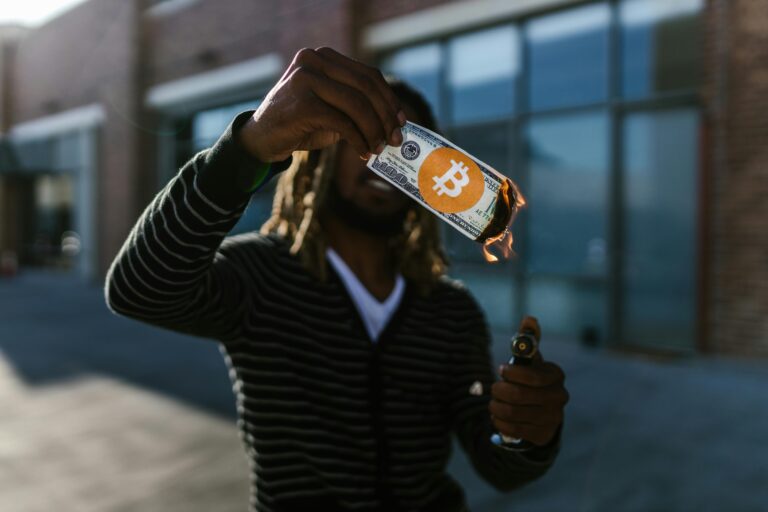 Man holding a burning dollar bill with Bitcoin symbol. Conceptual image of cryptocurrency impact. Inflacion